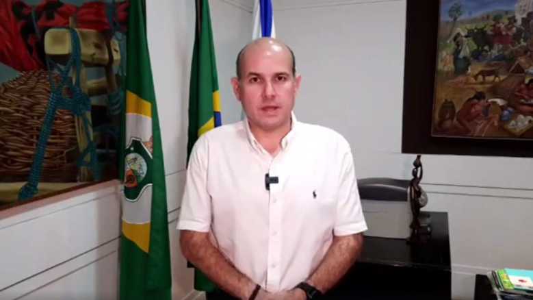 prefeito em pé posando para a foto em escritório com bandeira do Ceará ao fundo